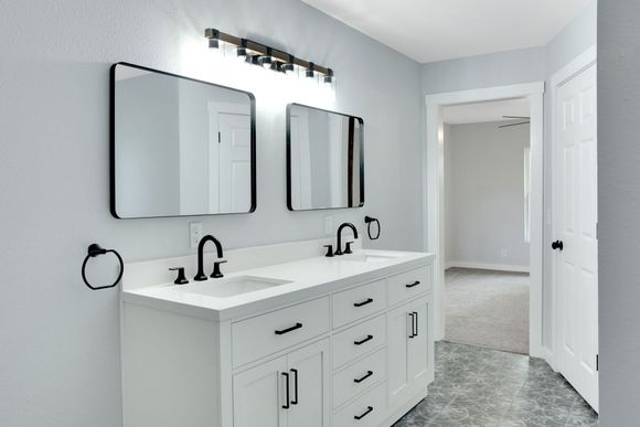 A walk-in shower with marble-patterned walls, two chrome showerheads, a white base, and a recessed ceiling light.