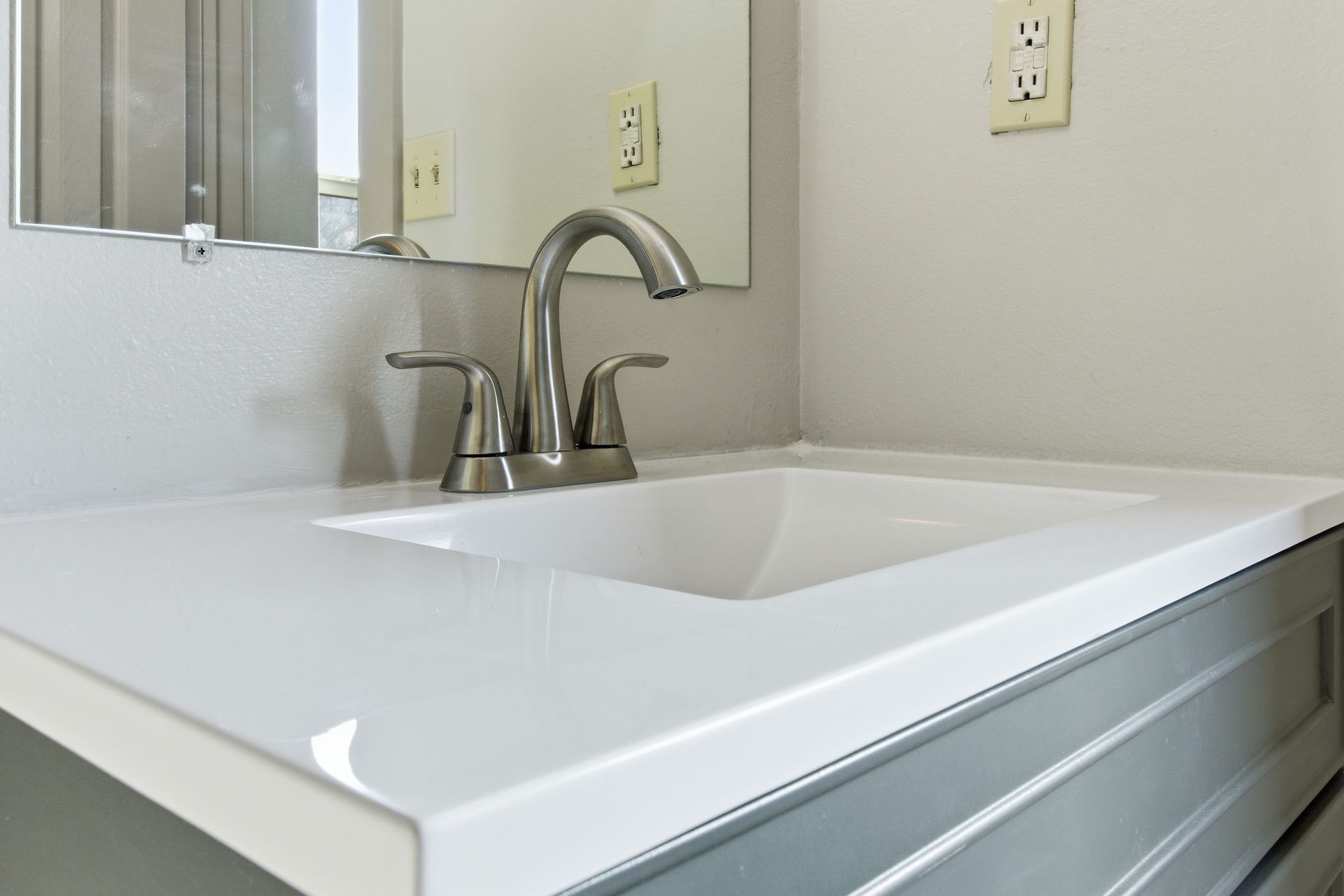 White bathroom sink with chrome faucet and mirror above it