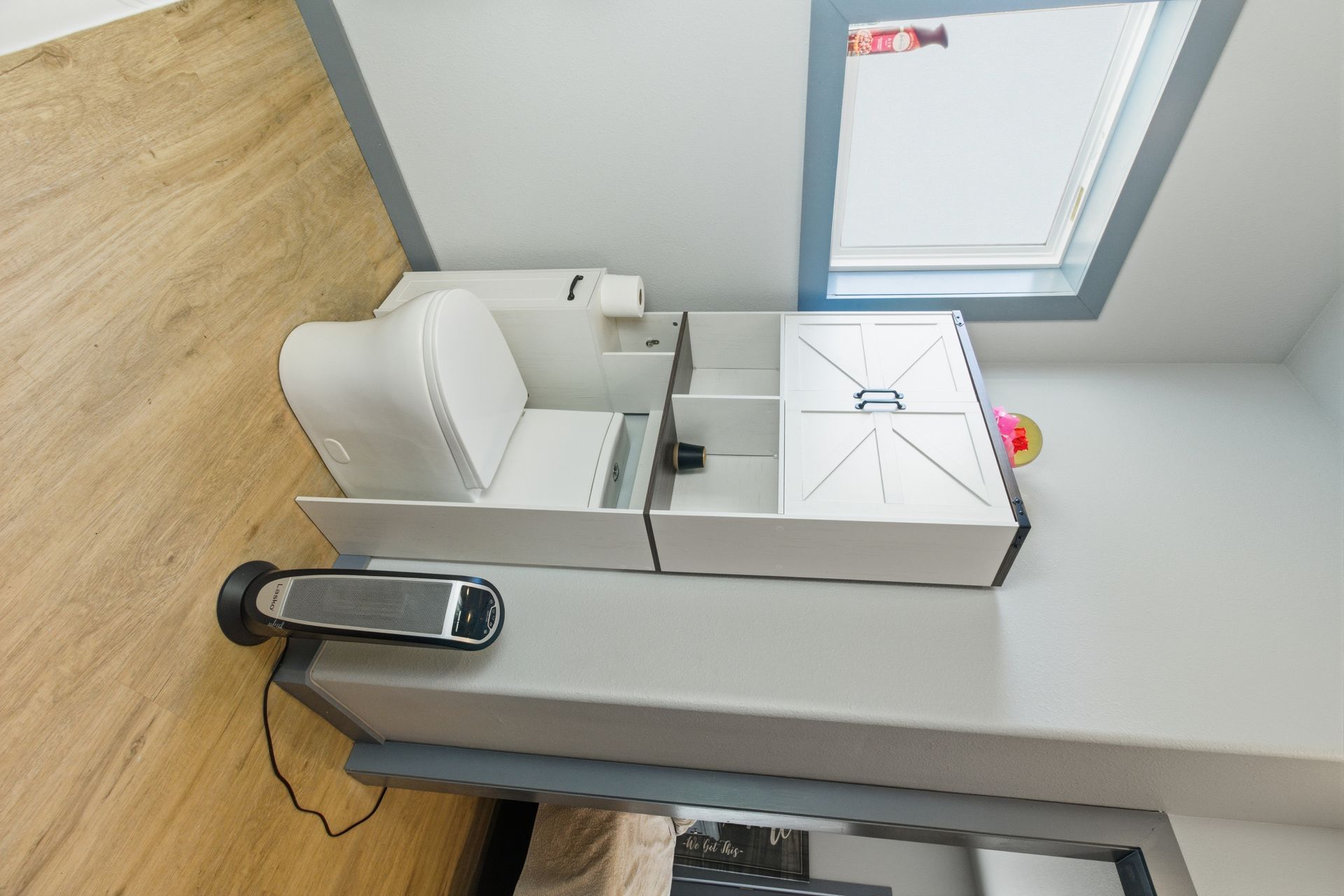 A high-angle view of a white modular station featuring a small seat, storage, and a flat surface, with a heater nearby.