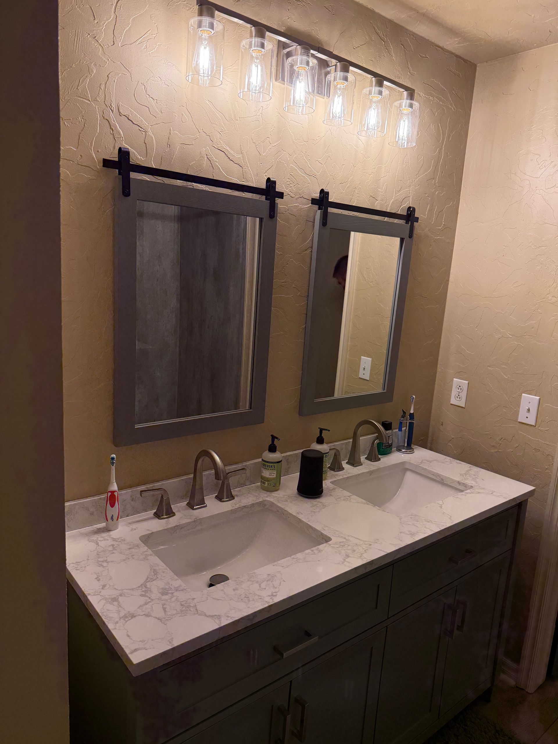 Double Fibo vanity bathroom with two mirrors, wall lights, sink, and white countertop.