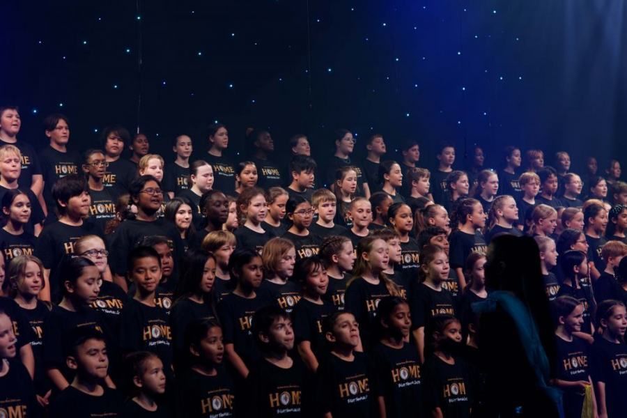 A large group of children are singing on a stage.