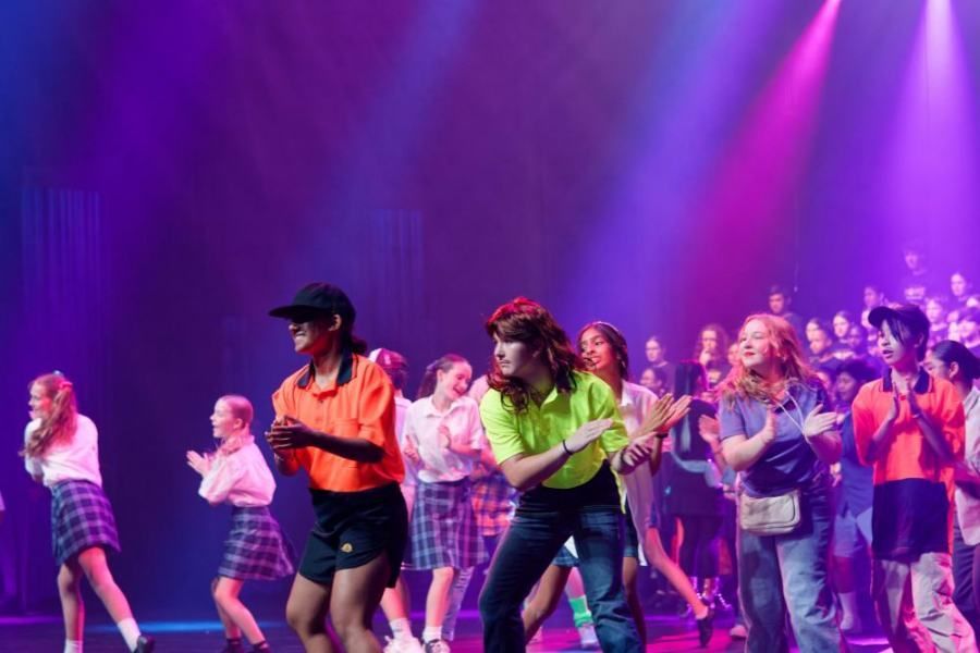 A group of people are dancing on a stage in front of a crowd.
