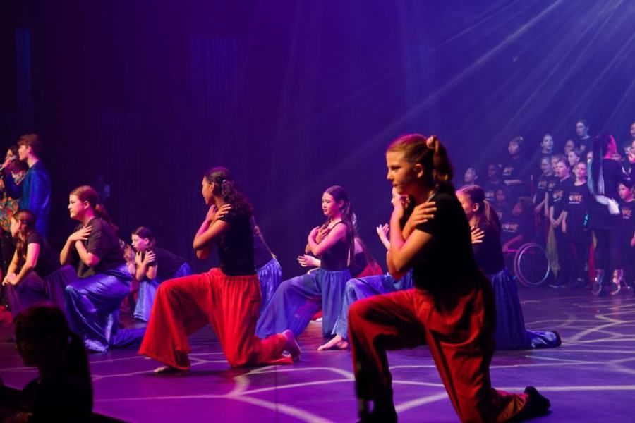A group of people are dancing on a stage in front of a crowd.