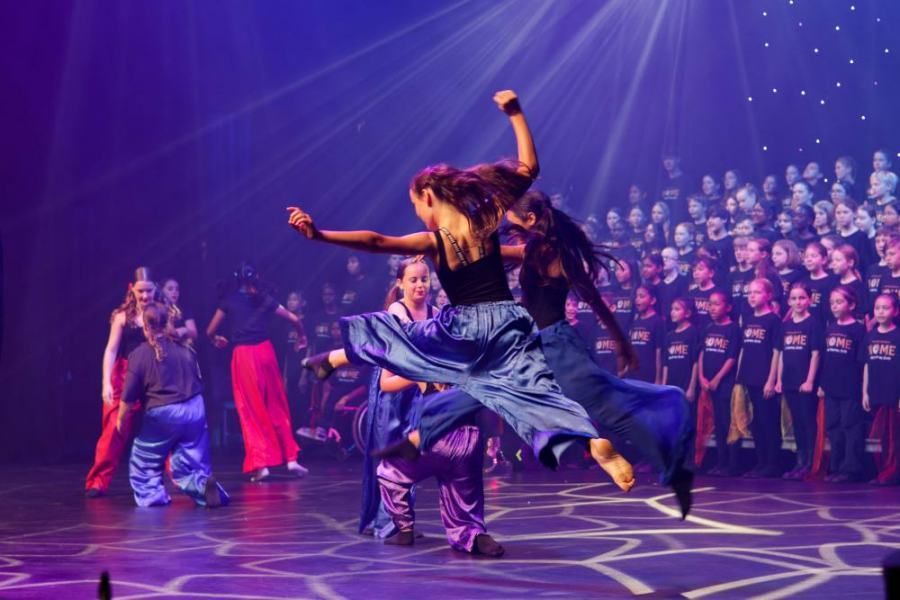 A group of people are dancing on a stage in front of a choir.