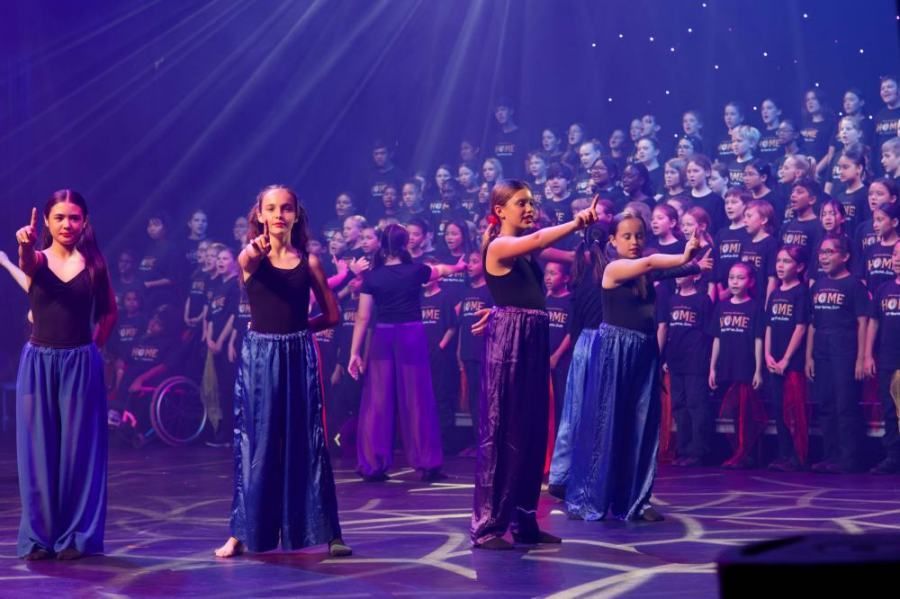A group of young girls are dancing on a stage in front of a large audience.