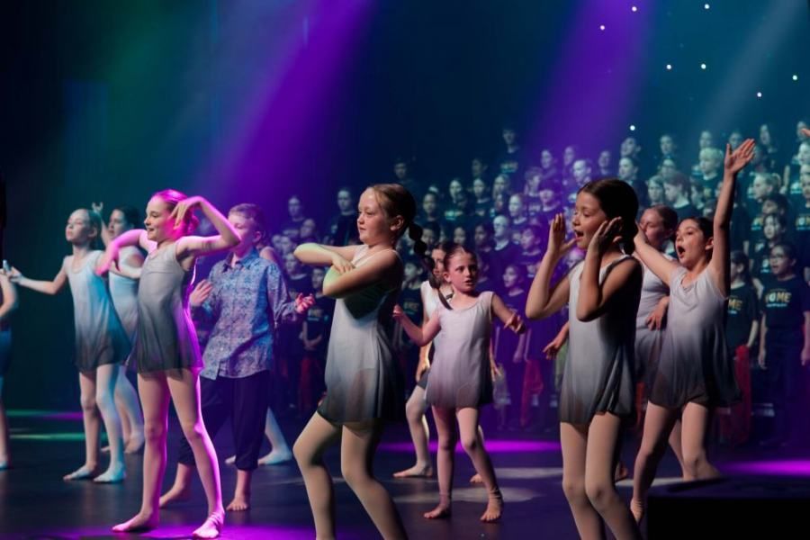 A group of young girls are dancing on a stage in front of a crowd.