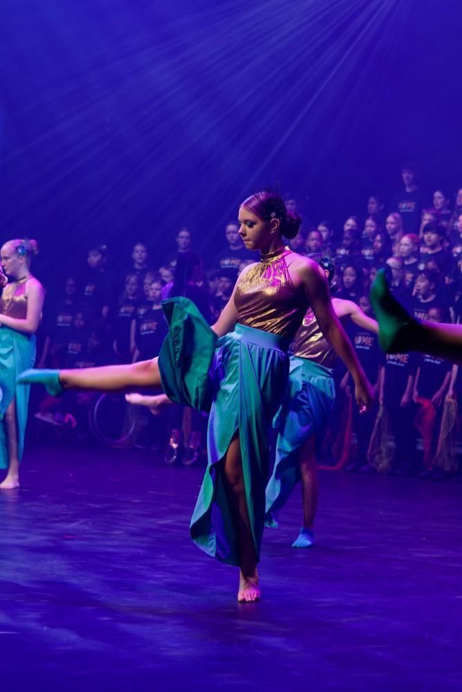 A group of women are dancing on a stage in front of a crowd.