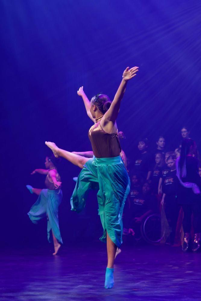 A group of dancers are performing on a stage in front of a crowd.