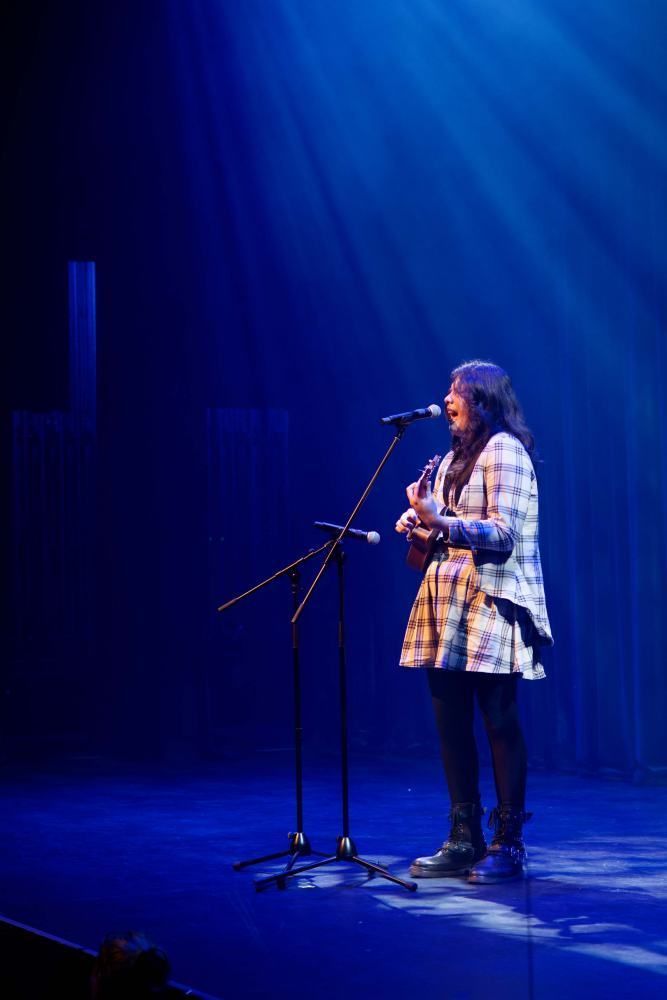 A woman is singing into a microphone on a stage.