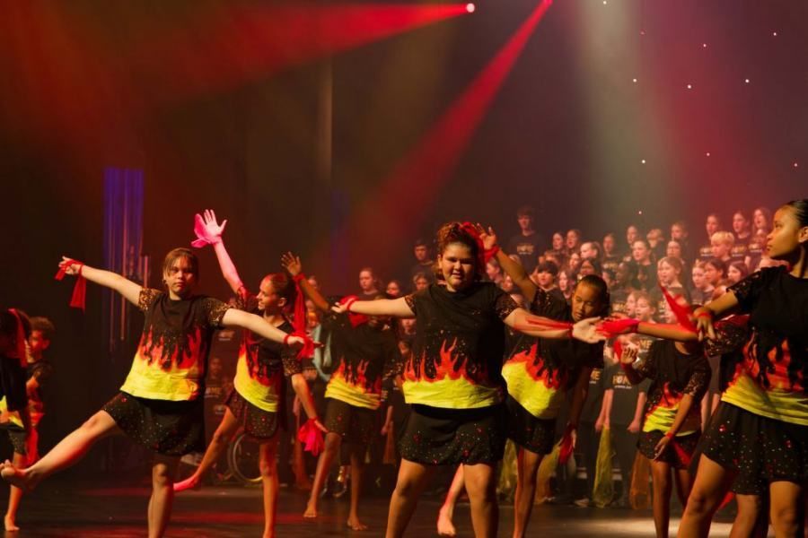 A group of young girls are dancing on a stage in front of a crowd.