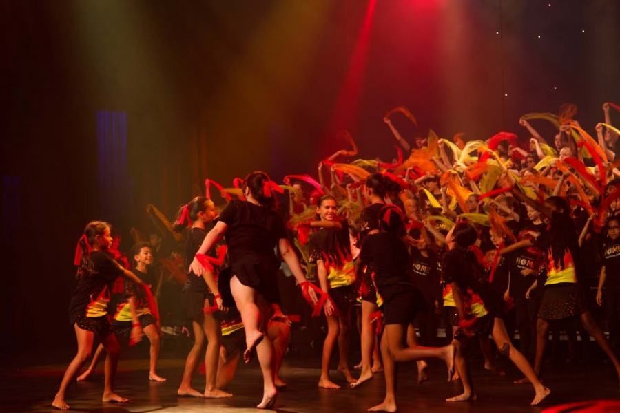 A group of people are dancing on a stage in a dark room.