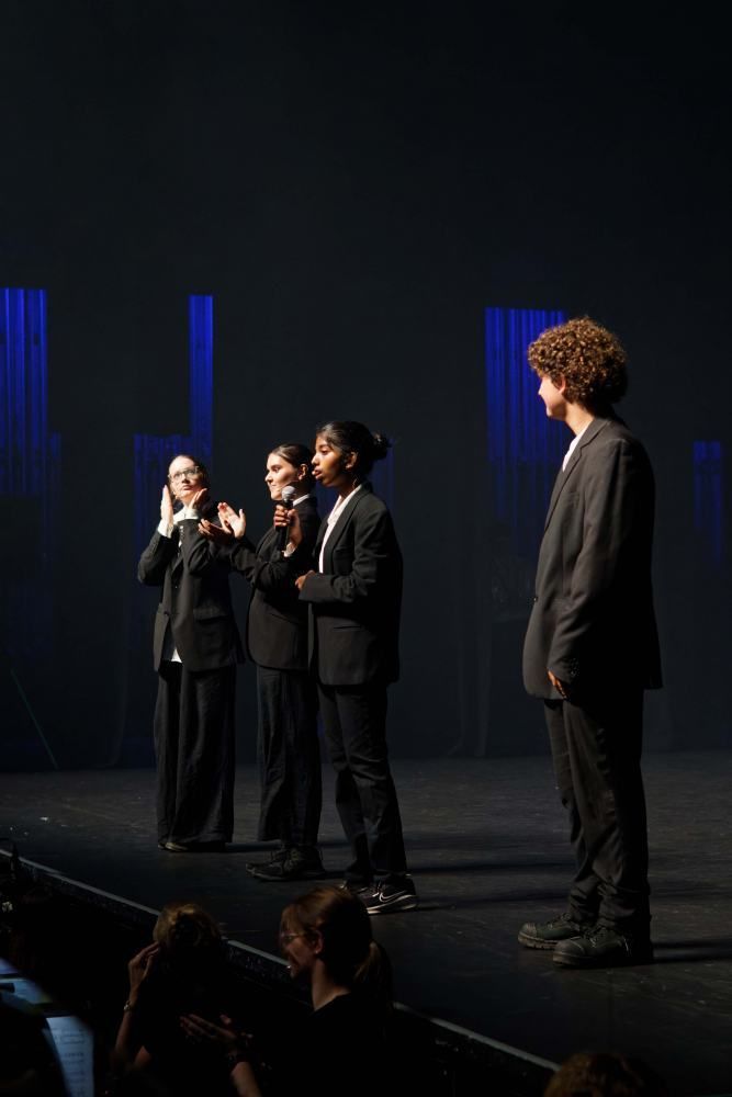A group of people are standing on a stage in front of a crowd.