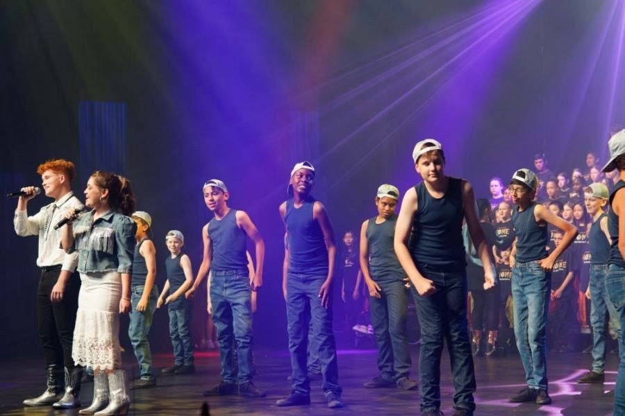 A group of people are standing on a stage in front of a microphone.