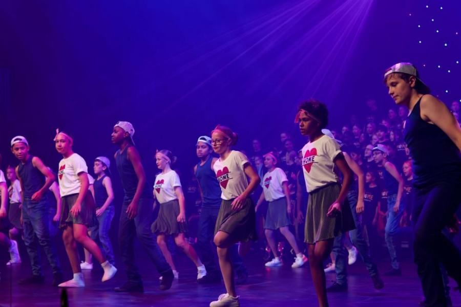 A group of young people are dancing on a stage in front of a crowd.