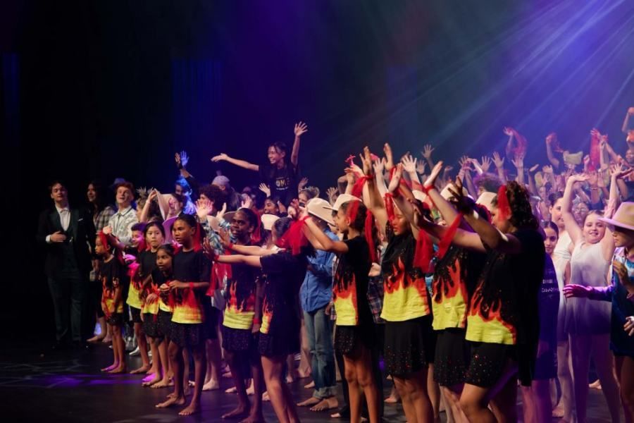 A large group of children are dancing on a stage.