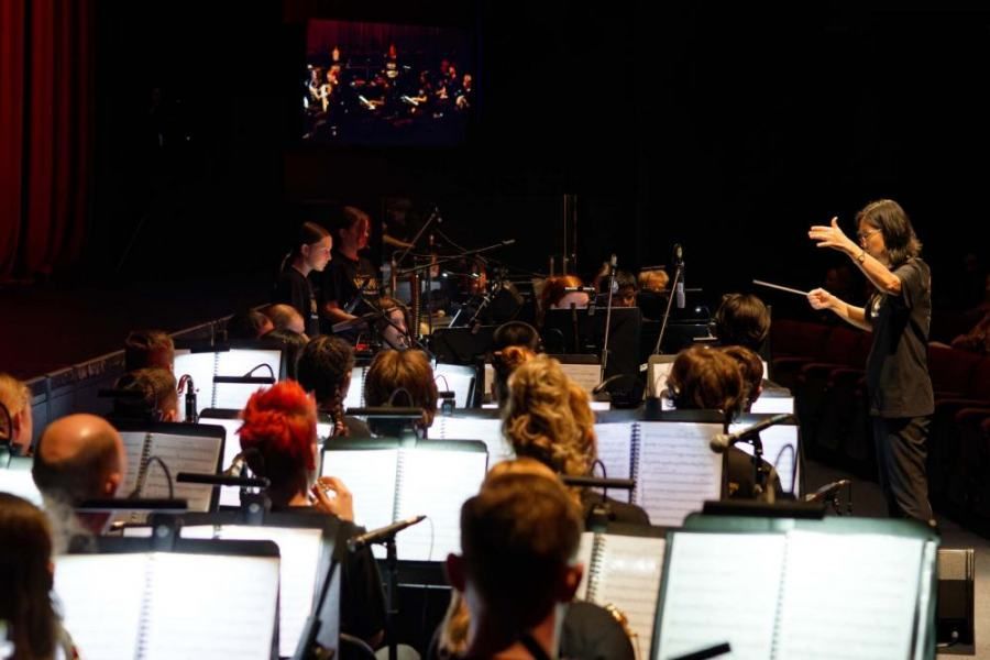 A woman is leading an orchestra on a stage.