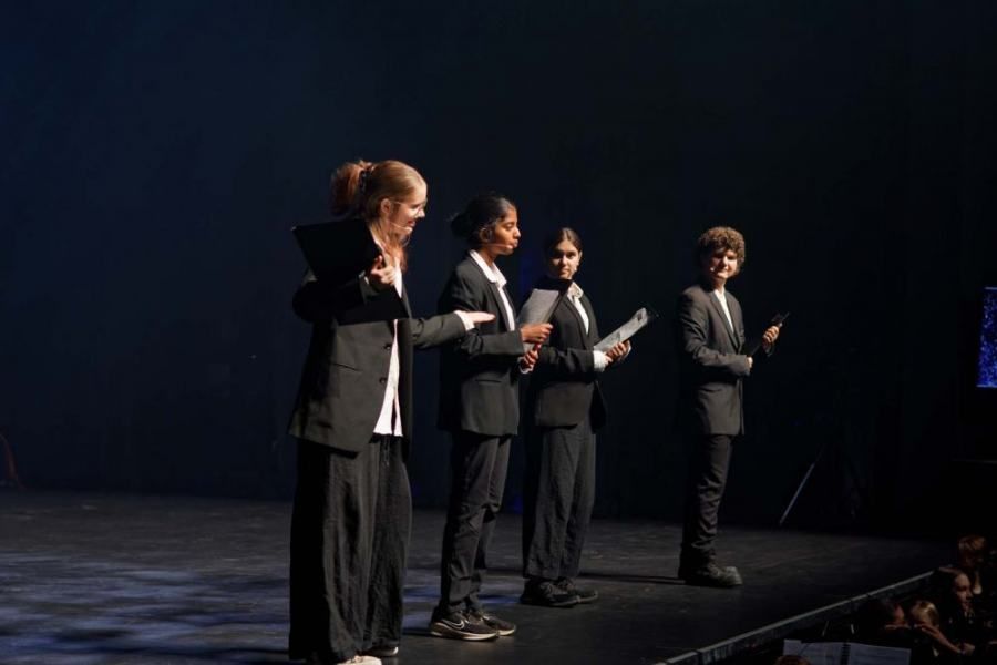 A group of people standing on a stage holding papers