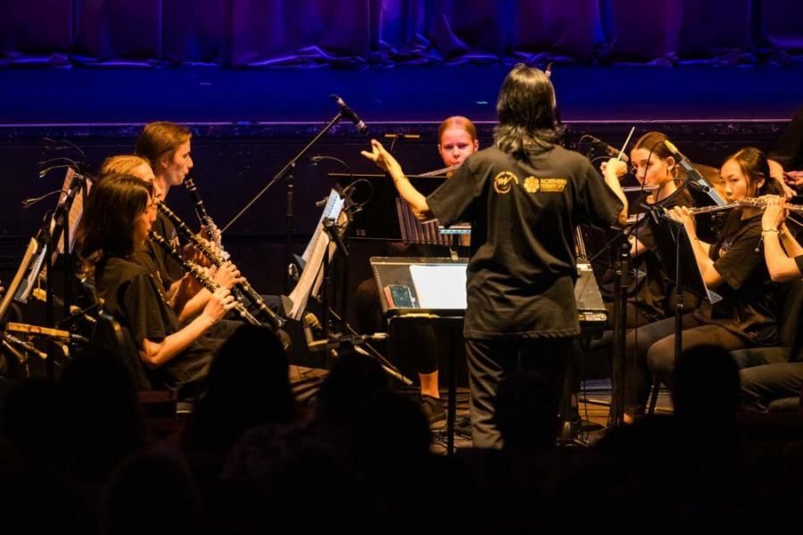 A woman is leading an orchestra on a stage.
