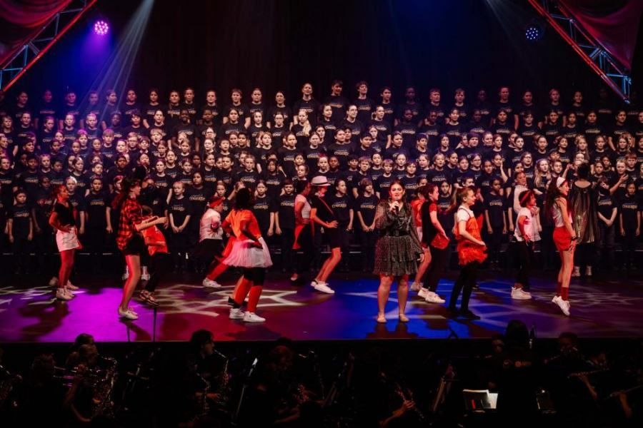 A group of people are dancing on a stage in front of a large choir.