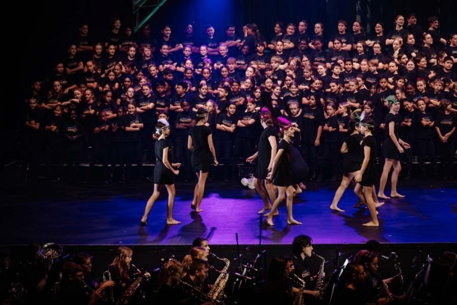 A group of people are dancing on a stage in front of a large choir.