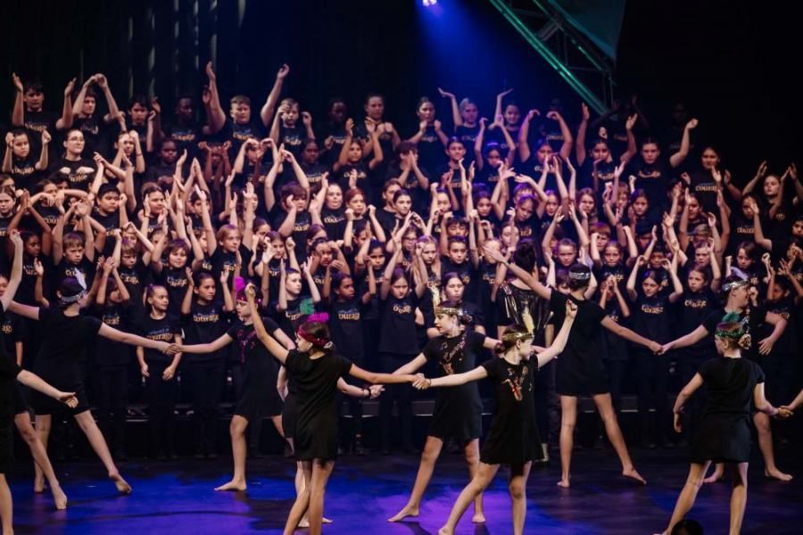 A large group of people are dancing on a stage.
