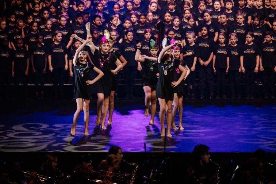 A group of people are dancing on a stage in front of a large choir.