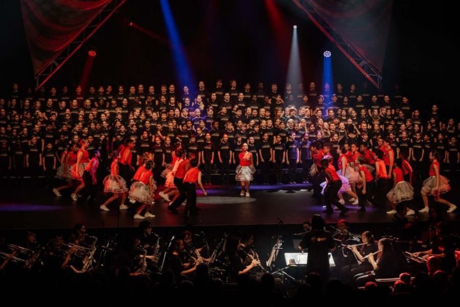 A group of people are dancing on a stage in front of a large choir.