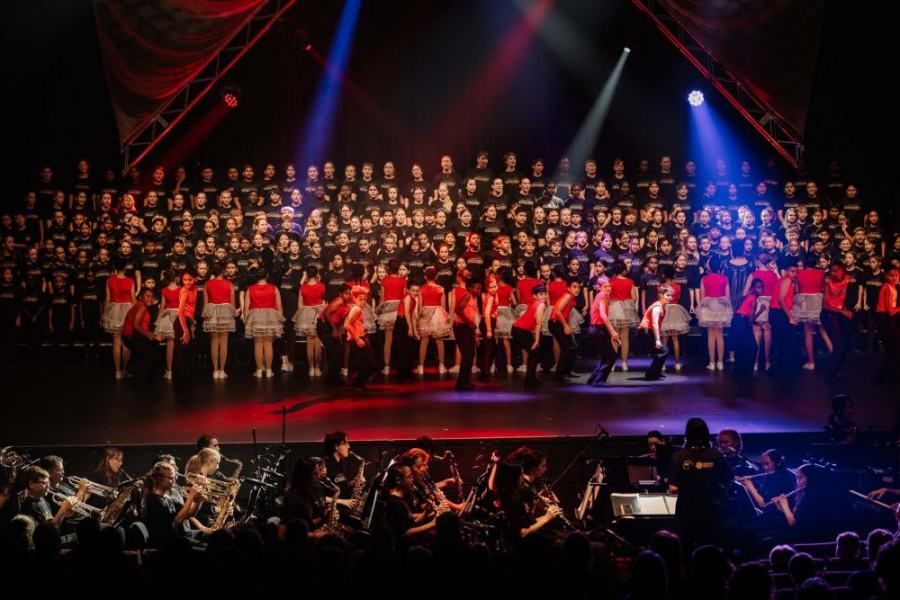 A large choir and orchestra are performing on a stage.