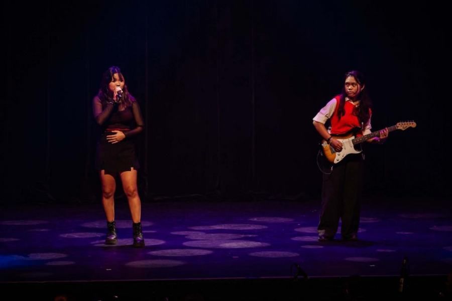 A man is playing a guitar and a woman is singing on a stage.