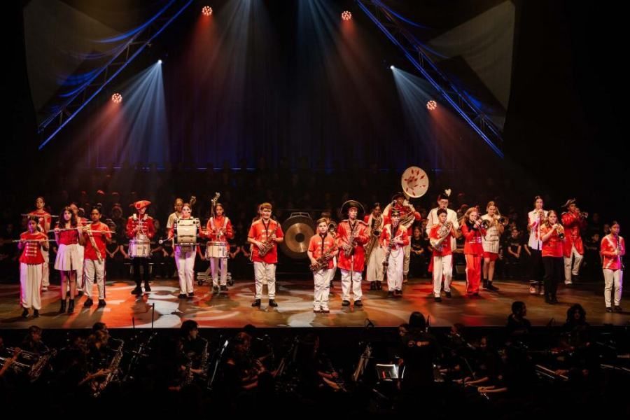 A band is playing instruments on a stage in front of a crowd.