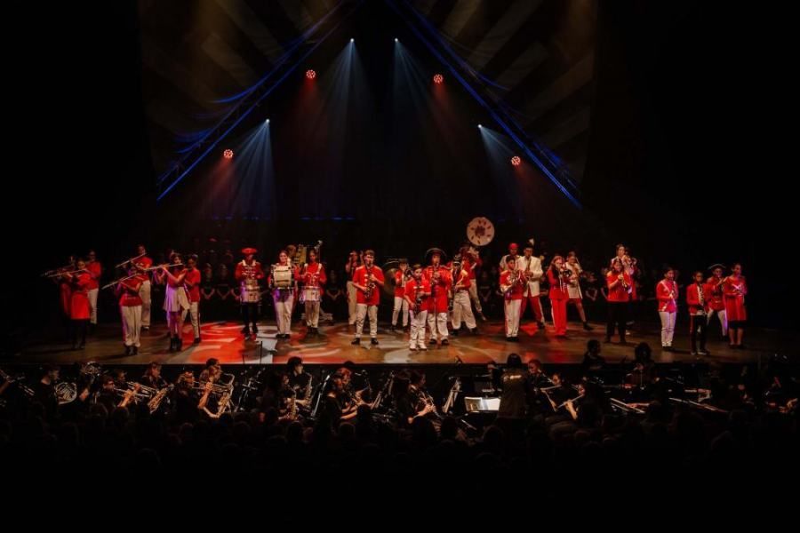 A large group of people are standing on a stage in front of a crowd.