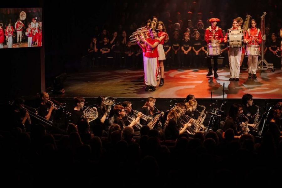 A band is playing instruments on a stage in front of a crowd.