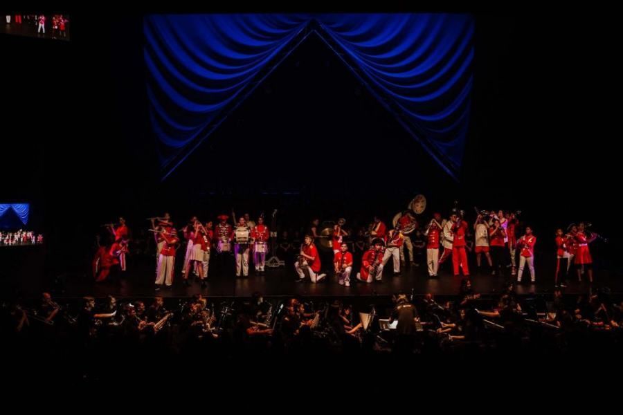 A group of people are standing on a stage in front of a blue curtain.