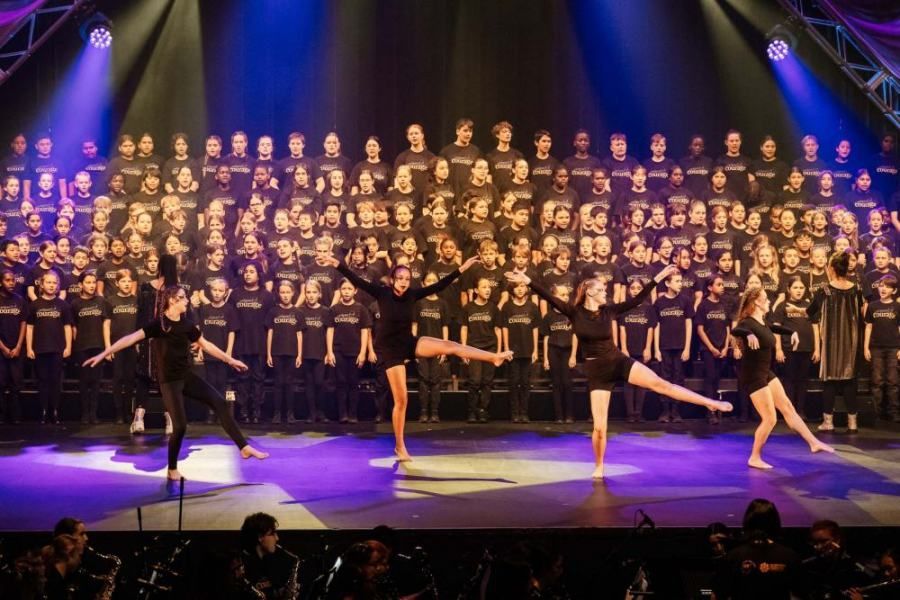 A group of people are dancing on a stage in front of a large choir.
