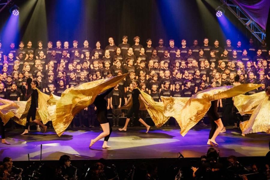 A group of people are dancing on a stage in front of a choir.