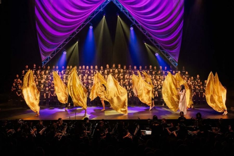 A group of people are dancing on a stage in front of a crowd.