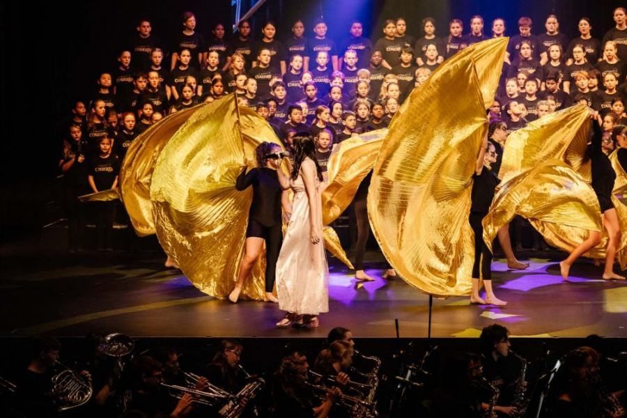 A group of people are dancing on a stage in front of a choir.