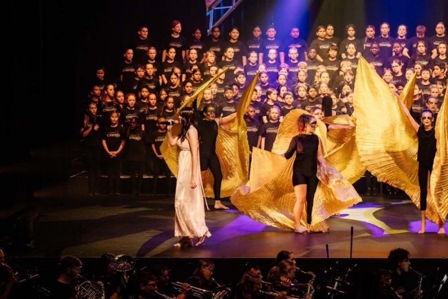 A group of people are dancing on a stage in front of a choir.