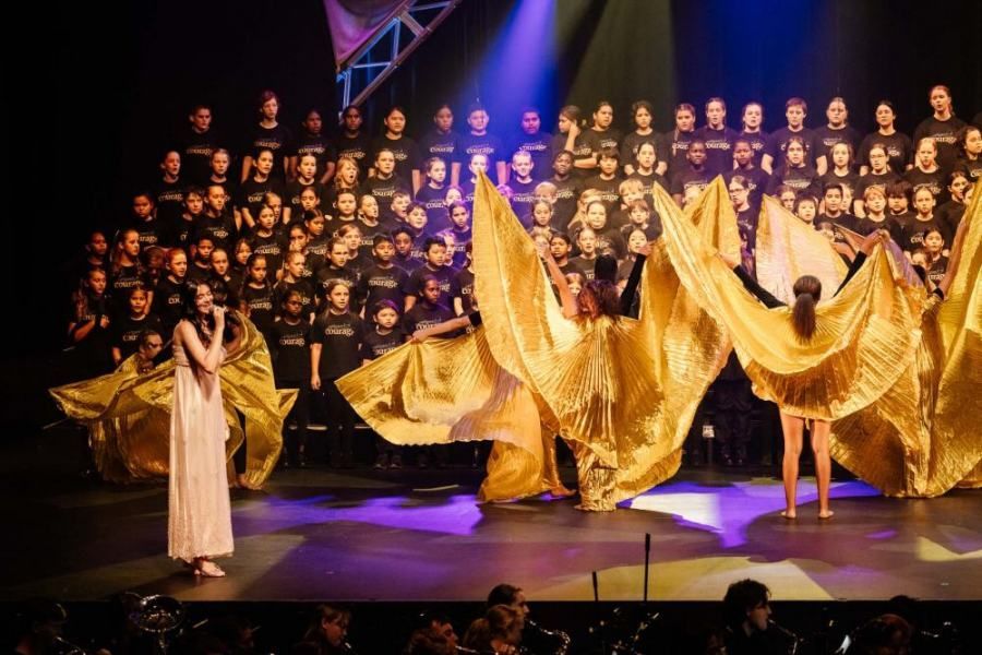A group of people are dancing on a stage in front of a choir.