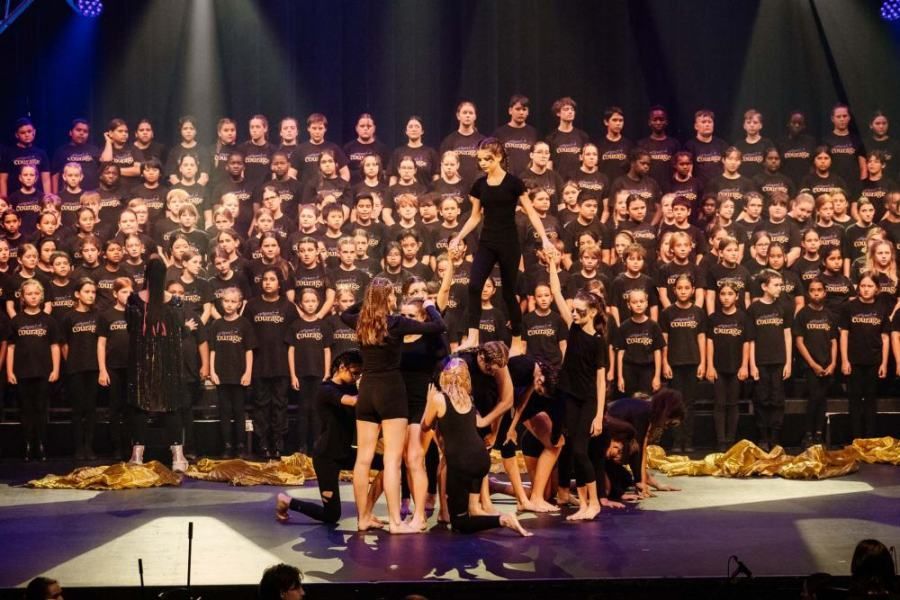 A group of people are dancing on a stage in front of a large choir