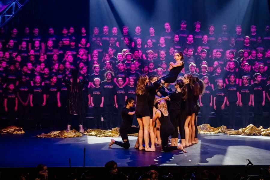A group of people are dancing on a stage in front of a choir.