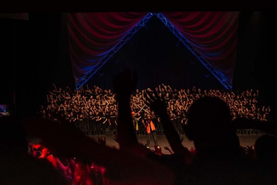 A crowd of people are standing in front of a stage at a concert.