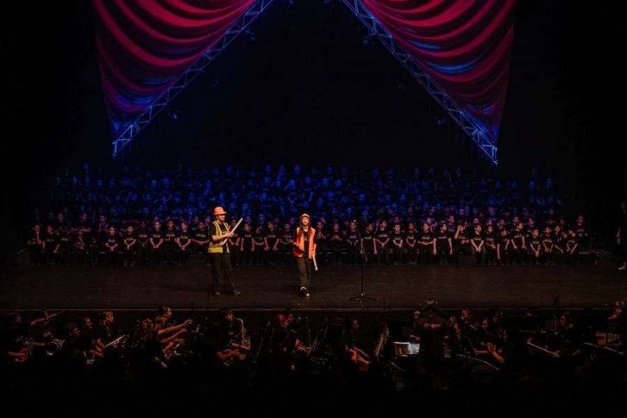 Two people are standing on a stage in front of a crowd.
