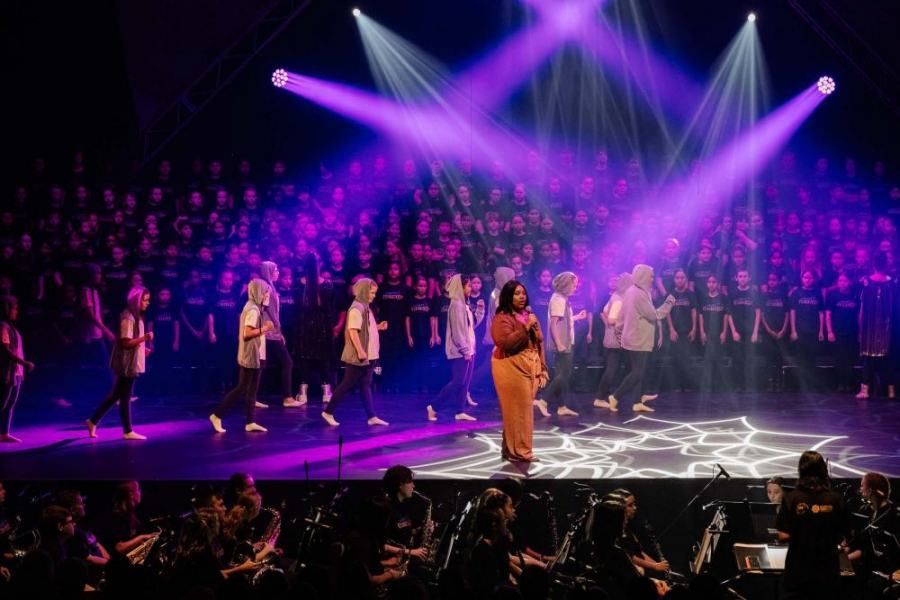 A group of people are standing on a stage with purple lights.