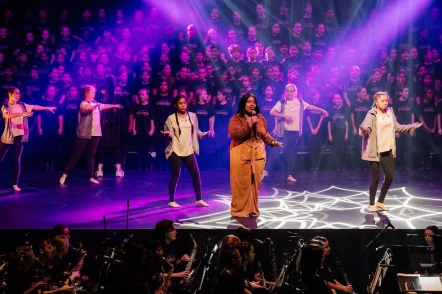 A group of people are dancing on a stage in front of a crowd.