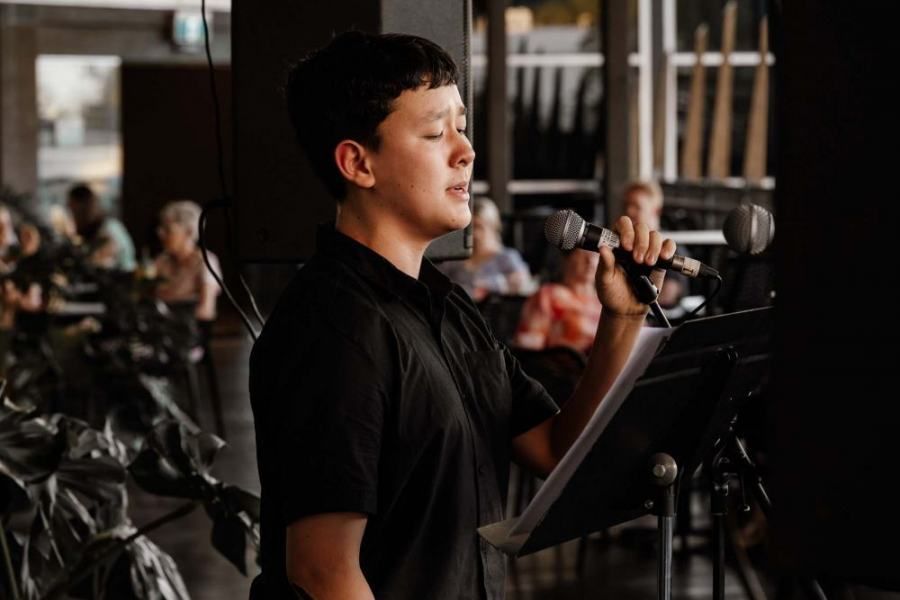 A young boy is singing into a microphone in a restaurant.