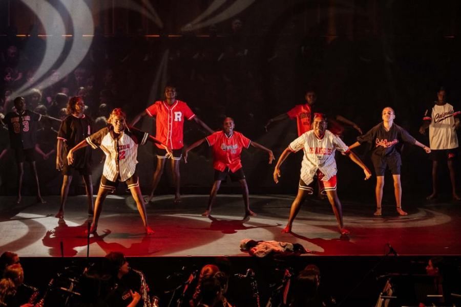 A group of people are dancing on a stage in front of a crowd.