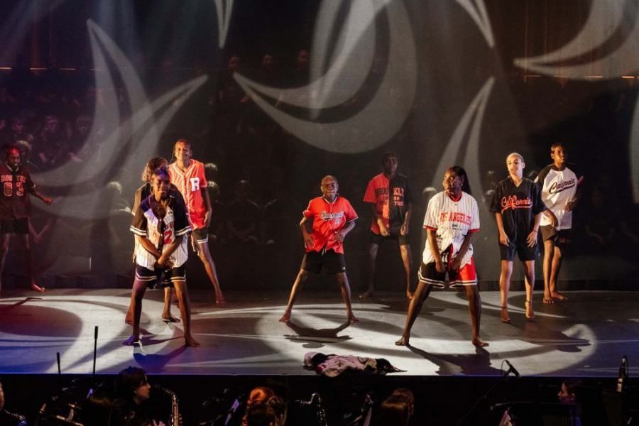 A group of people are dancing on a stage in front of a crowd.