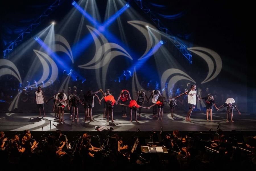 A group of people are dancing on a stage in front of a crowd.