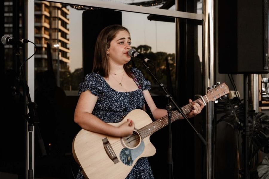 A woman is playing a guitar and singing into a microphone.